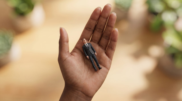 Miniature candidate figurine in a business suit resting gently on a recruiter's open palm