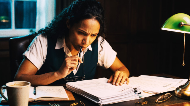 Focused recruiter reviewing a stack of resumes at her desk late at night