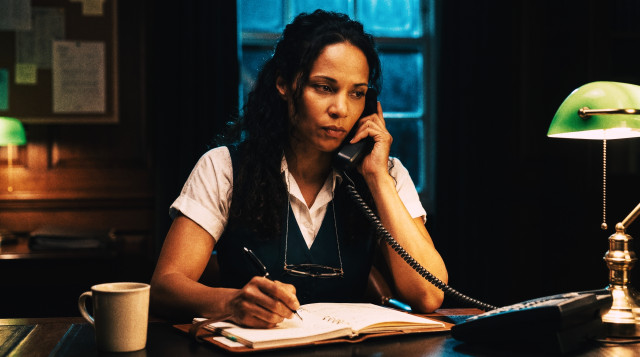 Recruiter conducting a phone screening interview while taking notes in a notebook