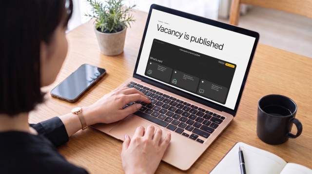 Woman using a laptop that shows the VideoApply dashboard with a "Vacancy is published" confirmation screen and a shareable job link