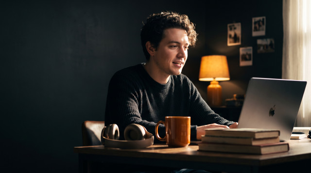Job candidate recording a one-way video interview answer on a laptop at a cozy home desk